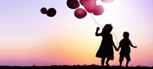 two-kids-outdoor-holding-balloons-together 2-1